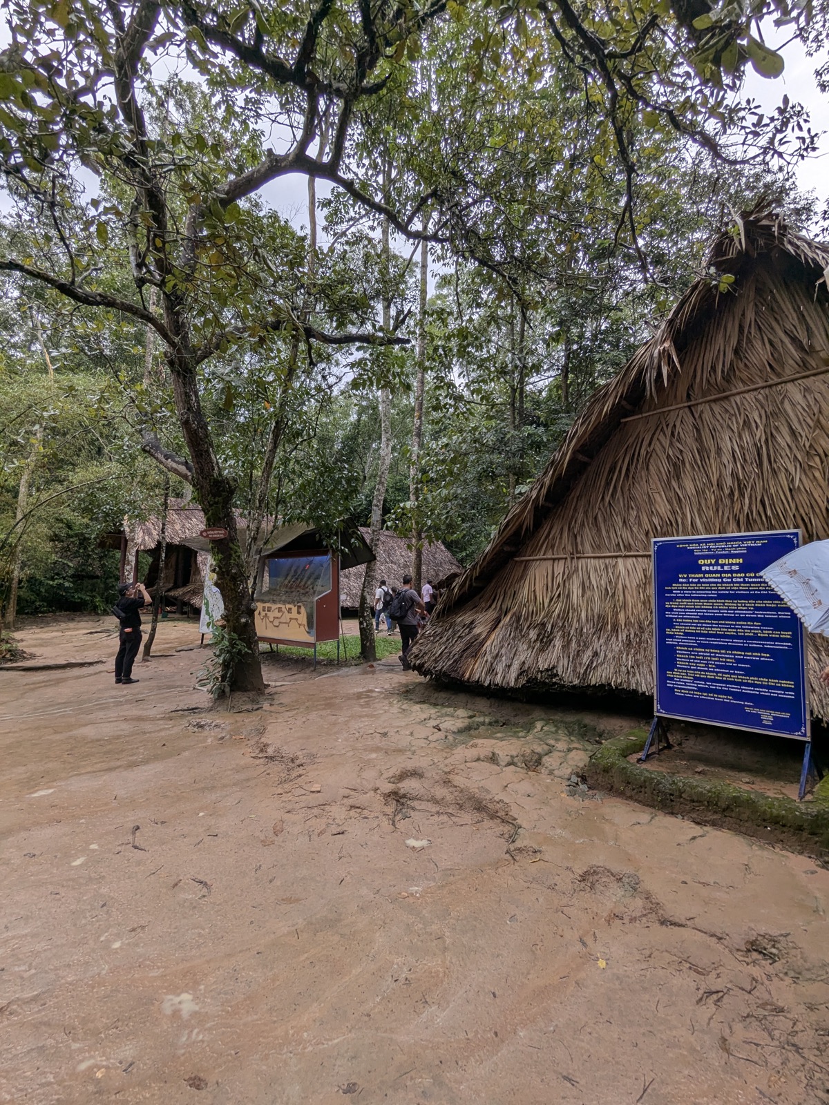 Palm-roofed structures among dense trees at the Cu Chi tunnels