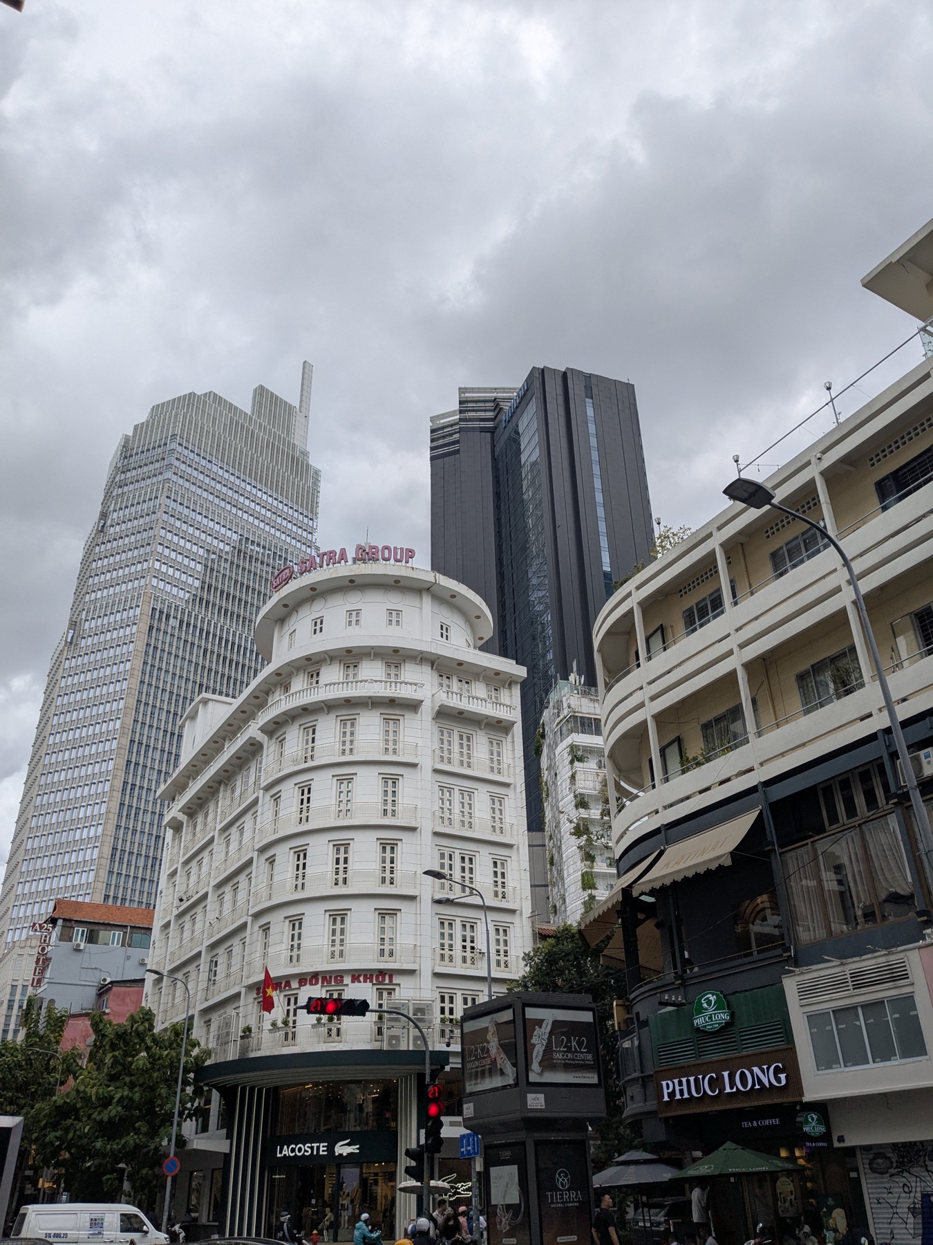Historic white corner building beneath modern towers in Ho Chi Minh City
